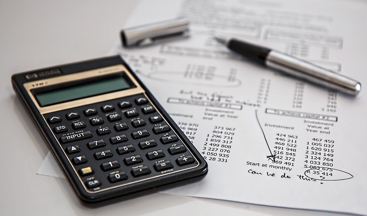 Calculadora e caneta sobre mesa, referência de preços de marketing digital para contabilidade em 2026